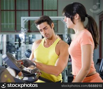 health club: woman walking on a tapis roulant with her personal trainer