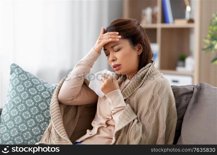 health, cold and people concept - sad sick young asian woman with paper tissue having headache at home. ill asian woman having headache at home