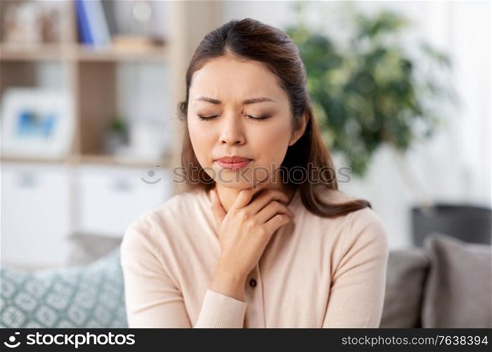 health, cold and people concept - sad sick young asian woman with sore throat at home. sick asian woman with sore throat at home