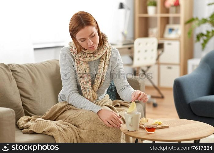 health, cold and people concept - sad sick young woman in drinking hot tea with lemon, honey and ginger at home. sad sick young woman drinking lemon tea at home