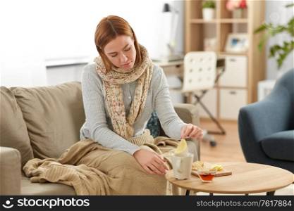 health, cold and people concept - sad sick young woman in drinking hot tea with lemon, honey and ginger at home. sad sick young woman drinking lemon tea at home