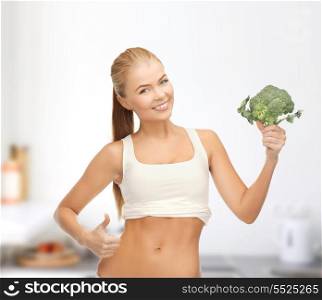 health, diet and food concept - beautiful woman pointing at her abs and holding broccoli