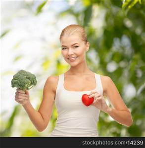 health, diet and food concept - young woman holding heart symbol and broccoli