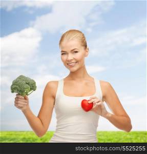 health, diet and food concept - young woman holding heart symbol and broccoli