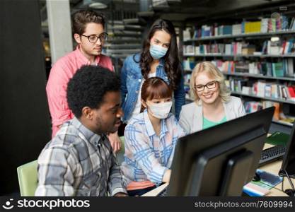 health, education and pandemic concept - group of happy smiling international students wearing protective medical mask for protection from virus with computers at school library. students in medical masks with computer at library