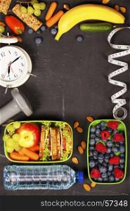 Health & Fitness Food in lunch boxes, measuring tape and alarm clock on wooden board. Diet food, health and fitness concept