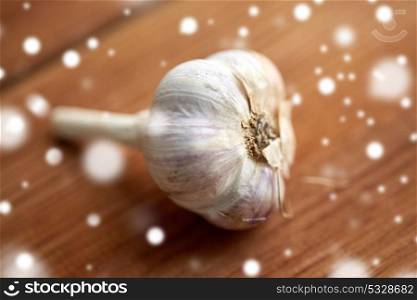 health, food, cooking, traditional medicine and ethnoscience concept - close up of garlic on wooden table over snow. close up of garlic on wooden table