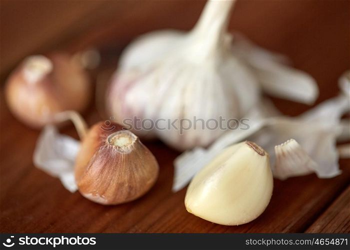 health, food, cooking, traditional medicine and ethnoscience concept - close up of garlic on wooden table