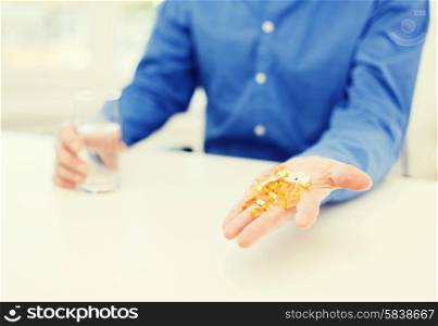 health, healthcare, medicine, medication and drugs concept - close up of male hand showing lot of pills