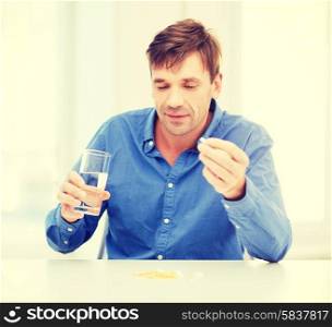 health, healthcare, medicine, medication, drugs, concept - ill man taking his pills at home