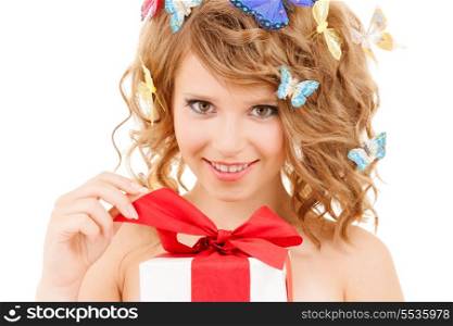 health, holidays and beauty concept - happy teenage girl with butterflies in hair opening gift box