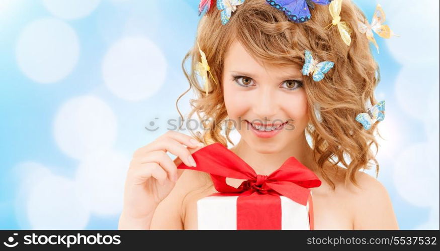 health, holidays and beauty concept - happy teenage girl with butterflies in hair opening gift box