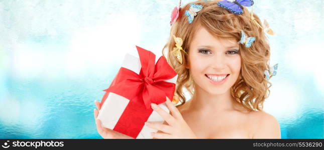 health, holidays and beauty concept - happy teenage girl with butterflies in hair showing gift box