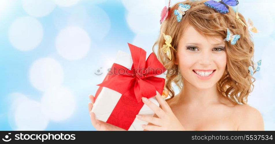 health, holidays and beauty concept - happy teenage girl with butterflies in hair showing gift box