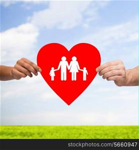 health, love, adoption and relationships concept - closeup of multiracial couple hands with big red heart with family and kids over blue sky with grass background