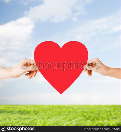 health, love and relationships concept - closeup of couple hands with big red heart