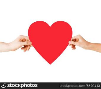 health, love and relationships concept - closeup of couple hands with big red heart