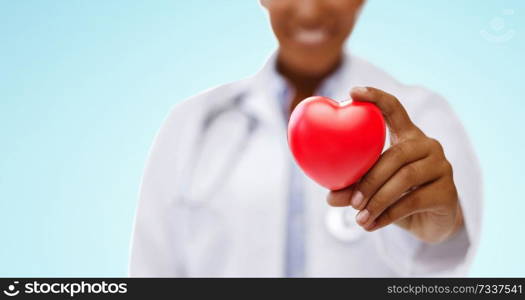 health, medicine and charity concept - close up of african american female doctor hand holding red heart over blue background. african american doctor hand holding red heart