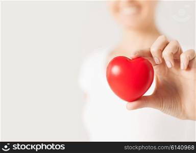 health, medicine and charity concept - close up of happy woman with small red heart