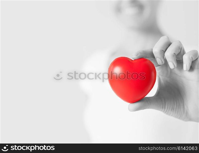 health, medicine and charity concept - close up of happy woman with small red heart