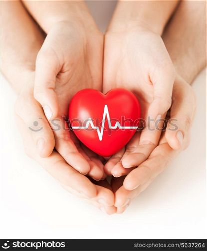 health, medicine and charity concept - closeup of couple hands holding red heart with ecg line
