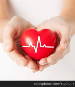 health, medicine and charity concept - closeup of female hands holding red heart with ecg line