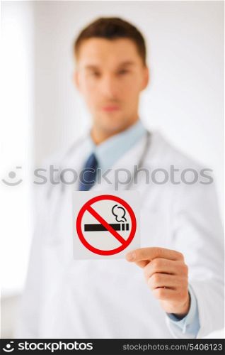 health, medicine and hospital concept - male doctor holding no smoking sign in hands