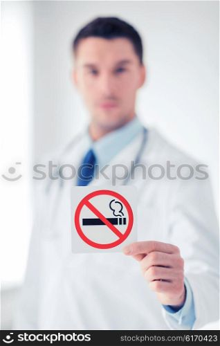 health, medicine and hospital concept - male doctor holding no smoking sign in hands