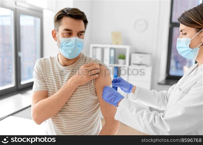 health, medicine and pandemic concept - female doctor or nurse in protective medical mask and gloves sticking patch to patient’s hand after vaccination at hospital. doctor applies patch to patient’s hand at hospital