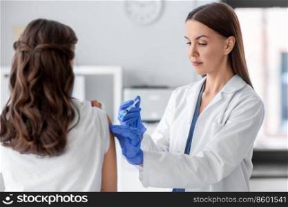 health, medicine and pandemic concept - female doctor or nurse wearing protective medical gloves with syringe vaccinating patient at hospital. female doctor with syringe vaccinating patient