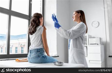 health, medicine and pandemic concept - smiling female doctor or nurse wearing protective medical gloves with syringe vaccinating patient at hospital. female doctor with syringe vaccinating patient
