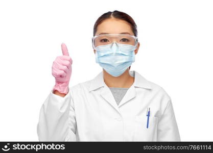 health, medicine and pandemic concept - young asian female doctor or scientist wearing goggles and face protective medical mask for protection from virus disease showing thumbs up. asian female doctor in mask showing thumbs up
