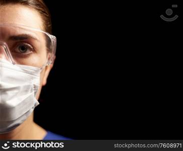 health, medicine and pandemic concept - young female doctor or nurse wearing goggles and face protective mask for protection from virus disease over black background. female doctor or nurse in goggles and face mask