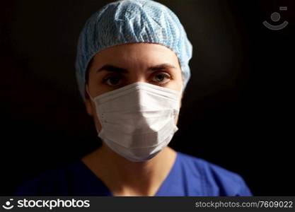 health, medicine and pandemic concept - young female doctor or nurse wearing face protective mask for protection from virus disease and hat over black background. doctor or nurse in medical face mask and hat