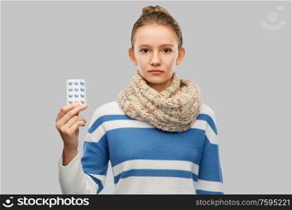 health, medicine and people concept - sick teenage girl in scarf with pills over grey background. sick teenage girl in scarf with medicine pills