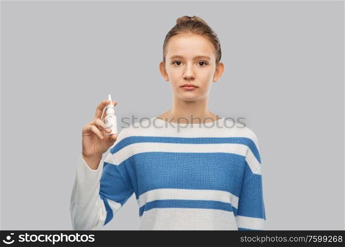 health, medicine and rhinitis concept - teenage girl with nasal spray over grey background. teenage girl with nasal spray over grey background