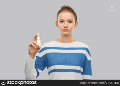 health, medicine and rhinitis concept - teenage girl with nasal spray over grey background. teenage girl with nasal spray over grey background
