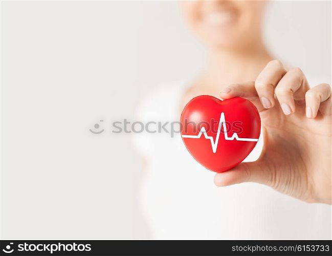 health, medicine, people and cardiology concept - close up of happy woman with cardiogram on small red heart