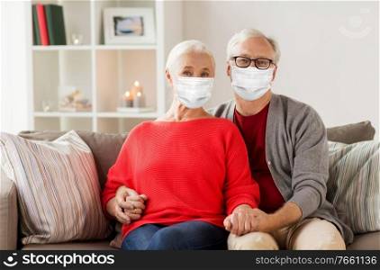 health, old age and people concept - senior couple wearing face protective medical mask for protection from virus disease on christmas at home. senior couple in masks on christmas at home