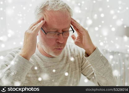 health, pain, stress and people concept - senior man suffering from headache at home over snow. senior man suffering from headache at home