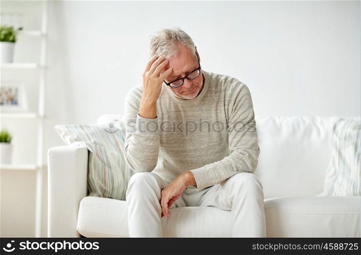 health, pain, stress, old age and people concept - senior man suffering from headache at home