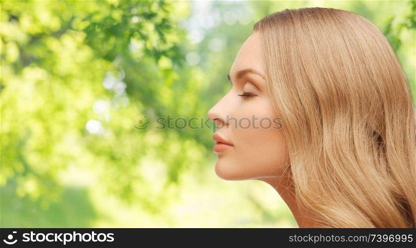 health, people and beauty concept - beautiful young woman face over green natural background. beautiful young woman face over natural background