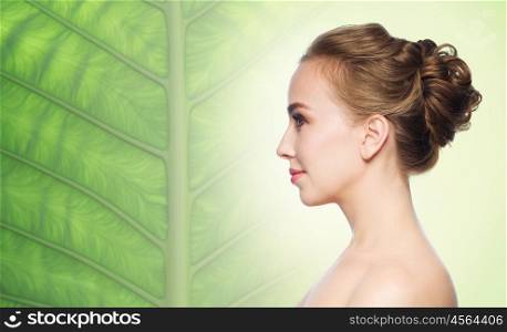 health, people and beauty concept - beautiful young woman face over natural green leaf background