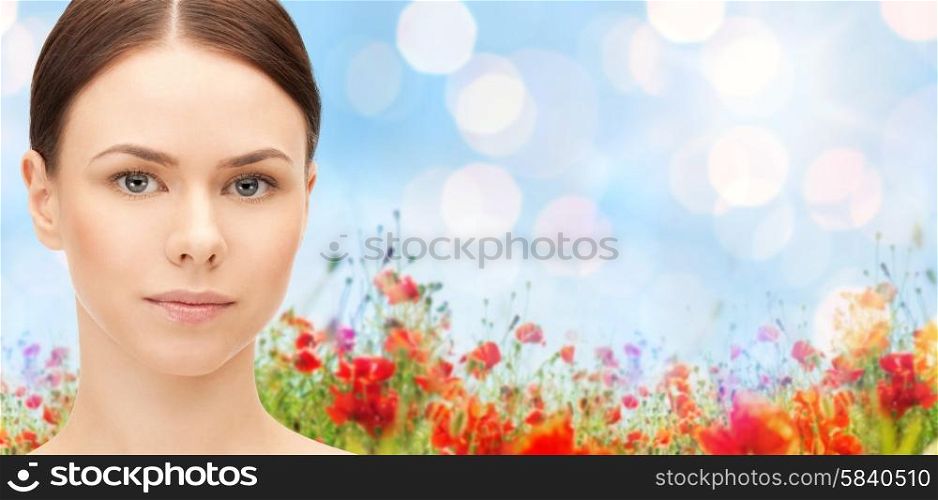 health, people and beauty concept - beautiful young woman face over poppy field background
