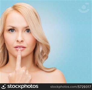 health, people and beauty concept - beautiful young woman touching her lips over blue background