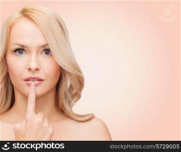 health, people and beauty concept - beautiful young woman touching her lips over pink background