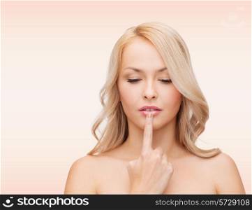 health, people and beauty concept - beautiful young woman touching her lips over pink background