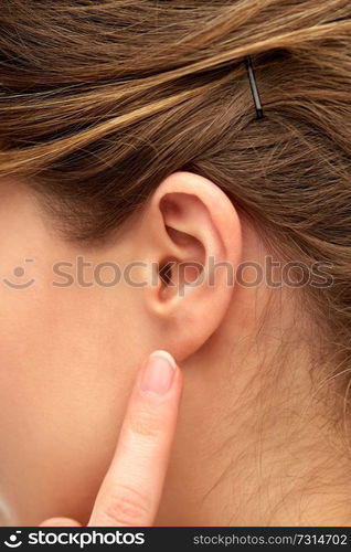 health, people and beauty concept - close up of young woman pointing finger to her ear. close up of young woman pointing finger to her ear