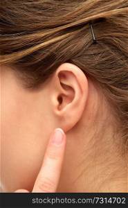 health, people and beauty concept - close up of young woman pointing finger to her ear. close up of young woman pointing finger to her ear