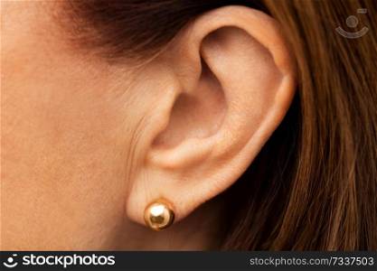 health, people and hearing concept - close up of senior woman ear with golden earring. close up of senior woman ear with golden earring